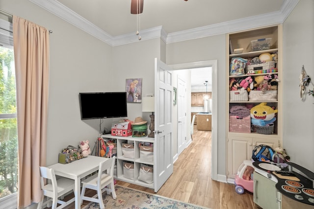 recreation room with ornamental molding, ceiling fan, and light hardwood / wood-style flooring