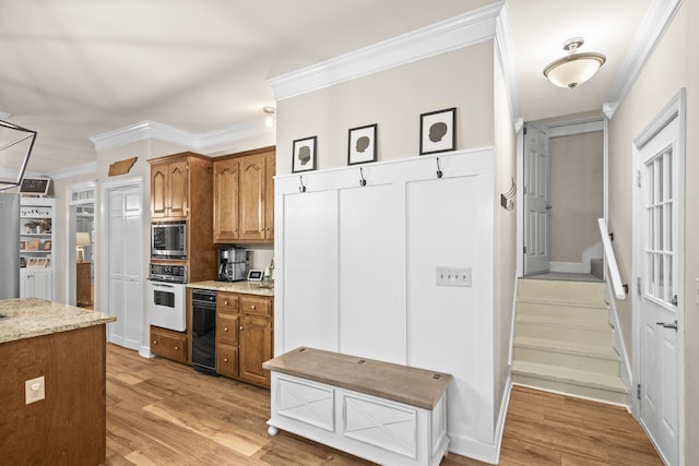 kitchen with light hardwood / wood-style flooring, oven, stainless steel microwave, and ornamental molding