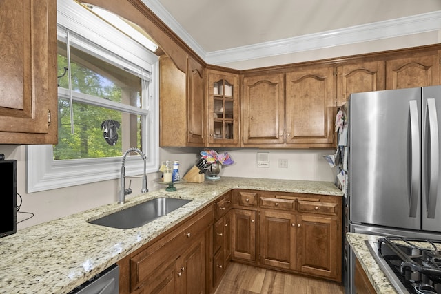 kitchen featuring light stone counters, sink, light hardwood / wood-style flooring, appliances with stainless steel finishes, and ornamental molding