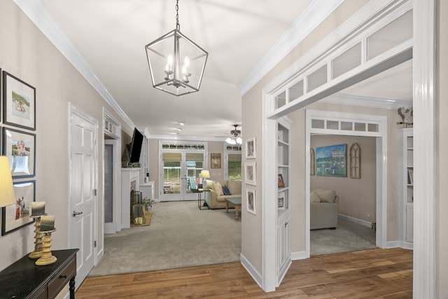 entryway featuring ceiling fan with notable chandelier, wood-type flooring, and ornamental molding