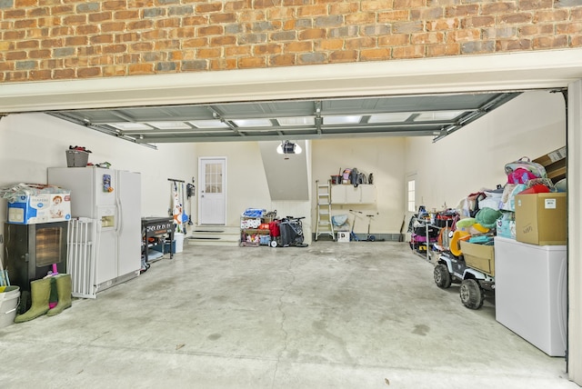 garage featuring white refrigerator with ice dispenser and a garage door opener