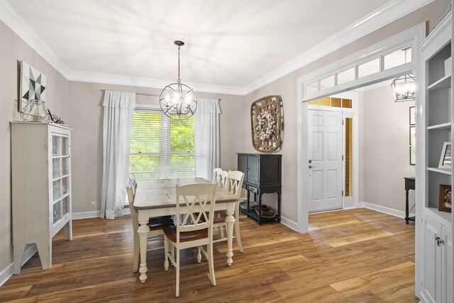 dining area featuring a notable chandelier, ornamental molding, and hardwood / wood-style flooring