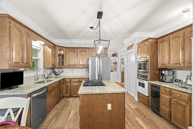 kitchen featuring hanging light fixtures, stainless steel appliances, light wood-type flooring, a center island, and sink