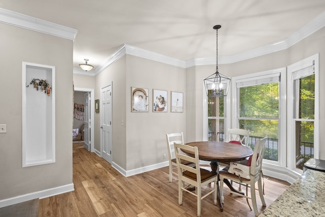 dining area with crown molding, light hardwood / wood-style flooring, and a notable chandelier