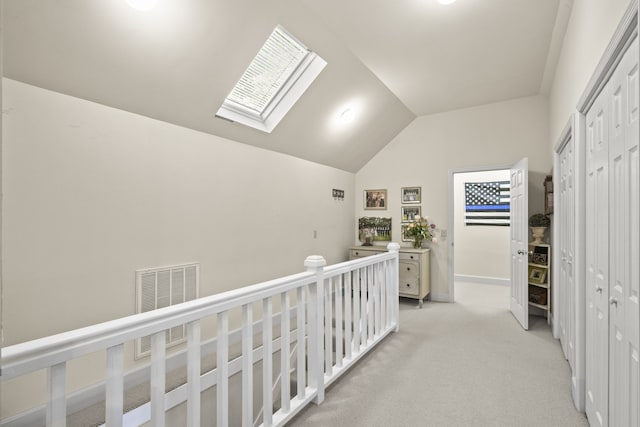 corridor with lofted ceiling with skylight and light carpet