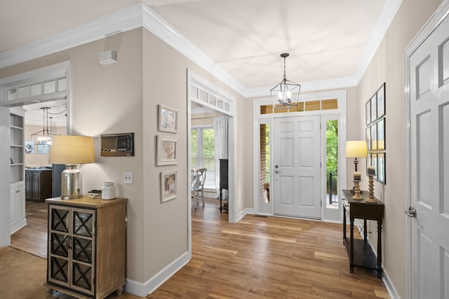 entrance foyer featuring ornamental molding, a chandelier, and hardwood / wood-style flooring