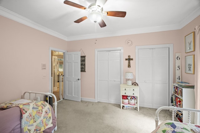 carpeted bedroom with multiple closets, ceiling fan, and crown molding