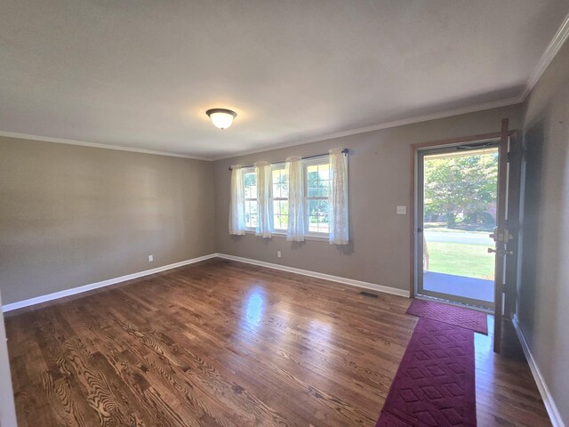 spare room with ornamental molding and dark hardwood / wood-style flooring