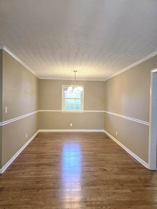 spare room featuring crown molding, dark hardwood / wood-style floors, and a chandelier