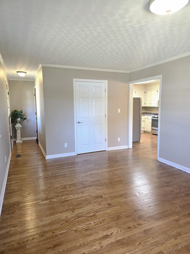 empty room featuring ornamental molding and dark hardwood / wood-style flooring