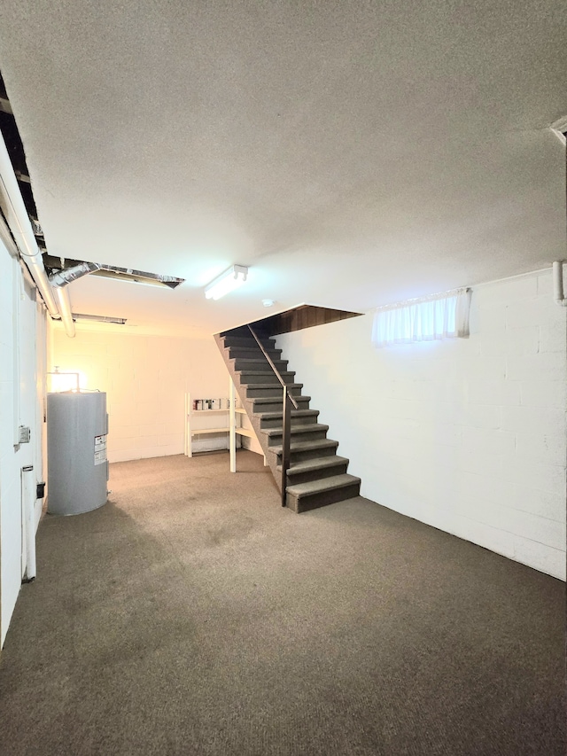 basement featuring electric water heater, a textured ceiling, and carpet flooring