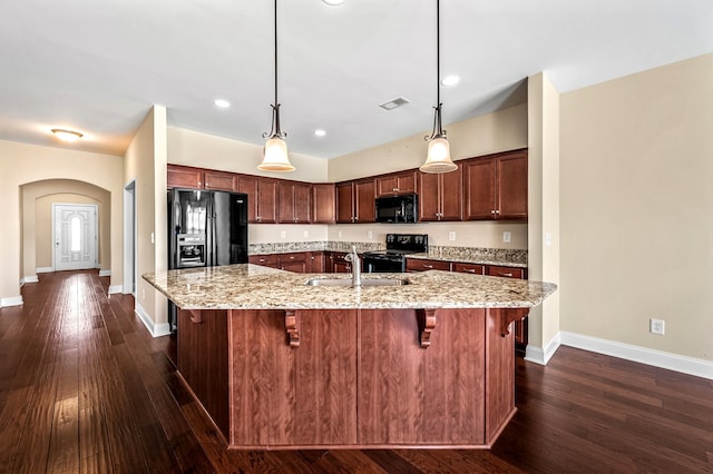 kitchen featuring light stone counters, sink, dark wood-type flooring, black appliances, and a kitchen breakfast bar