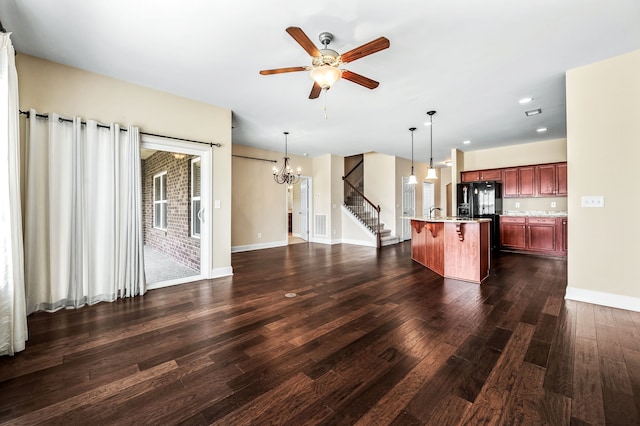 unfurnished living room with ceiling fan with notable chandelier, dark wood-type flooring, and sink