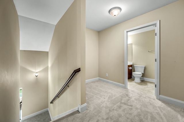 hall featuring lofted ceiling and light colored carpet