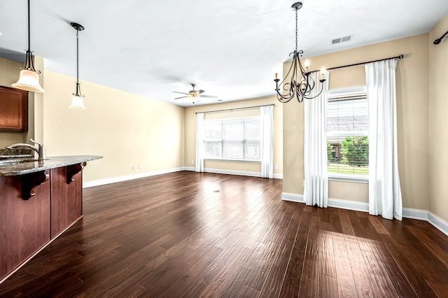 unfurnished living room featuring ceiling fan with notable chandelier, dark wood-type flooring, and sink