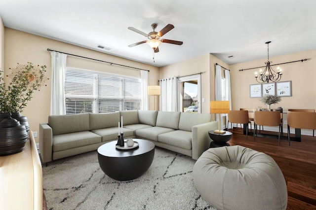 living room with ceiling fan with notable chandelier and dark hardwood / wood-style floors