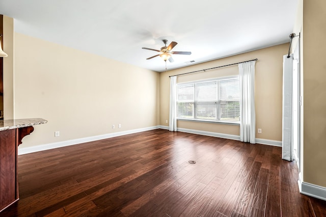 unfurnished room with ceiling fan and dark wood-type flooring