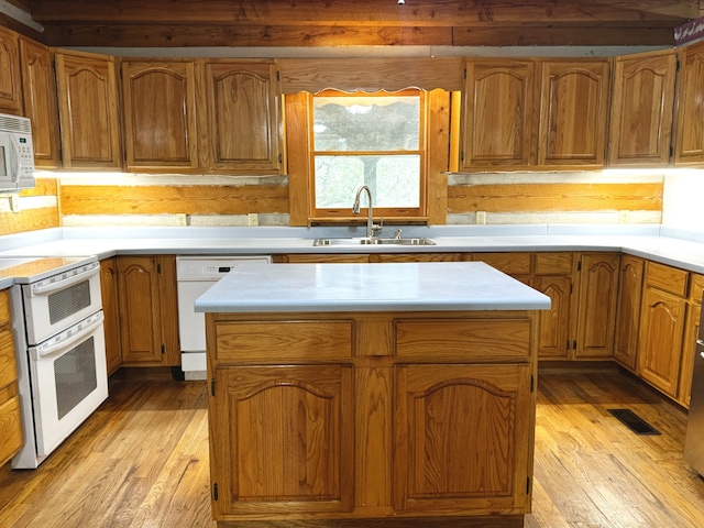 kitchen featuring a center island, light wood-type flooring, and white appliances