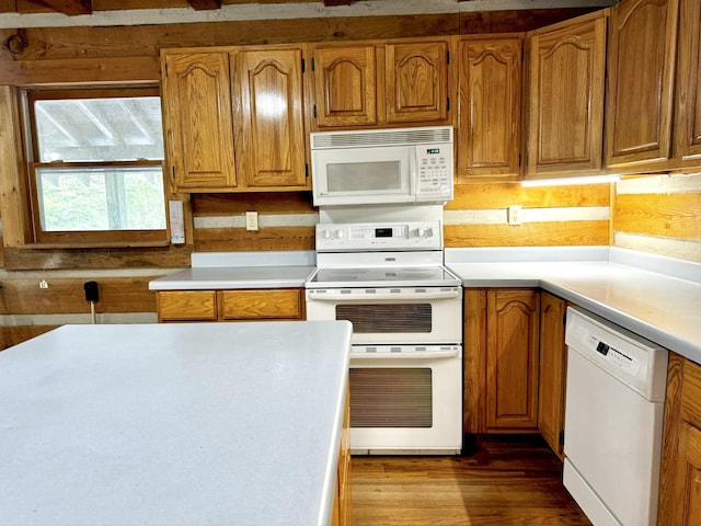 kitchen featuring light countertops, brown cabinetry, dark wood-style flooring, and white appliances