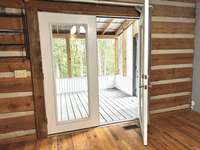 doorway with hardwood / wood-style floors and visible vents