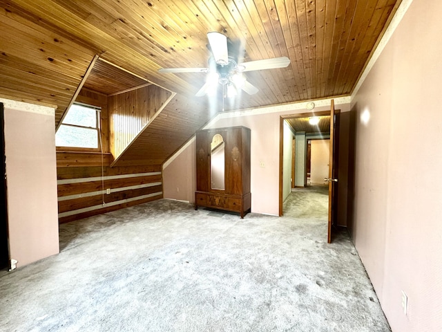 bonus room with ceiling fan, light colored carpet, wood ceiling, and wooden walls