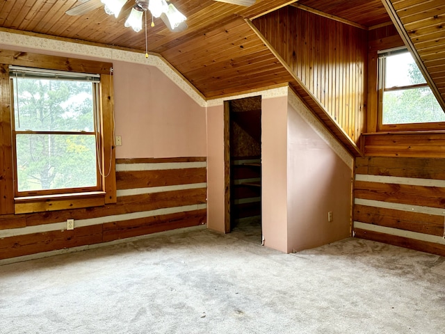 additional living space featuring carpet, lofted ceiling, wooden walls, ceiling fan, and wood ceiling