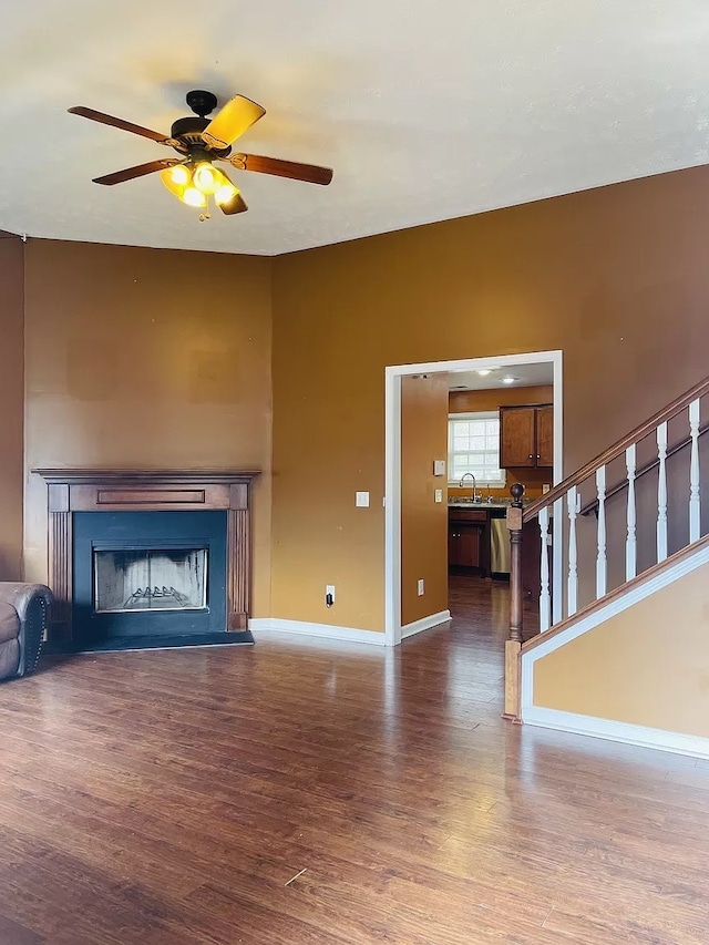 unfurnished living room with ceiling fan, sink, and dark hardwood / wood-style flooring