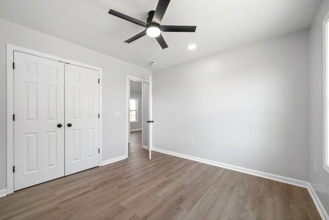 unfurnished bedroom featuring ceiling fan, a closet, and light hardwood / wood-style flooring