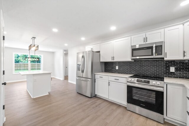 kitchen featuring white cabinetry, light hardwood / wood-style floors, appliances with stainless steel finishes, and hanging light fixtures