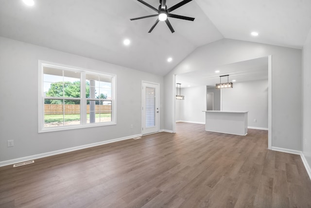 unfurnished living room with ceiling fan with notable chandelier, lofted ceiling, and dark wood-type flooring