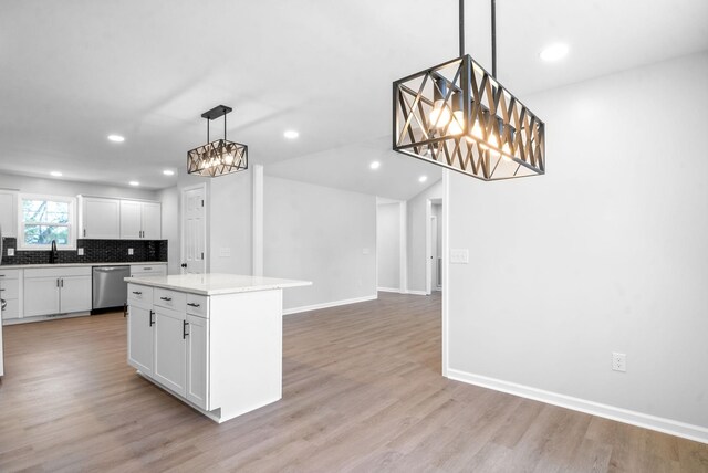 kitchen featuring light wood-type flooring, dishwasher, white cabinetry, a kitchen island, and decorative light fixtures