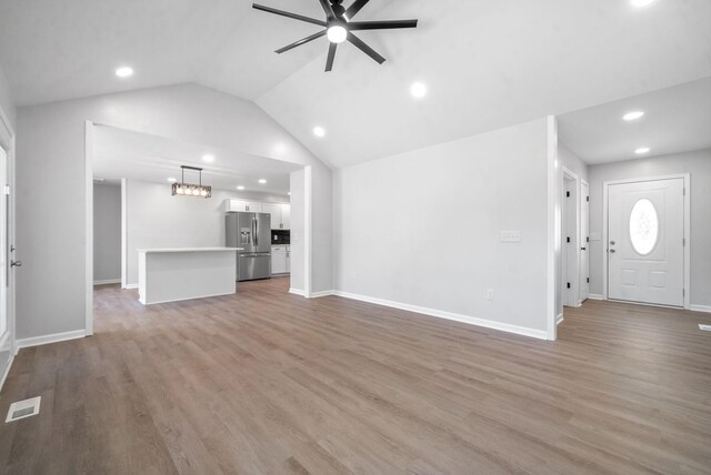 unfurnished living room featuring light wood-type flooring, vaulted ceiling, and ceiling fan