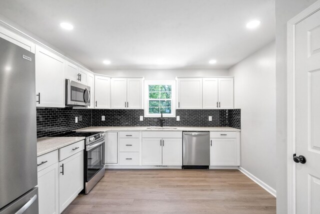 kitchen featuring stainless steel appliances, light wood-type flooring, sink, and white cabinetry