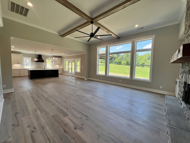 unfurnished living room featuring ceiling fan with notable chandelier, a fireplace, ornamental molding, and hardwood / wood-style flooring