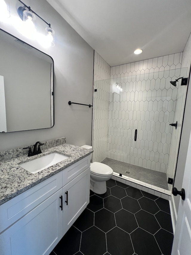 bathroom featuring vanity, tile patterned floors, toilet, and tiled shower