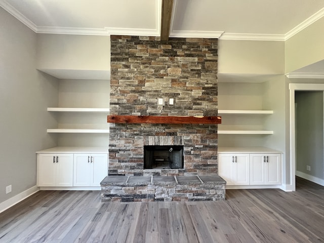 unfurnished living room featuring a stone fireplace, hardwood / wood-style flooring, built in features, and ornamental molding