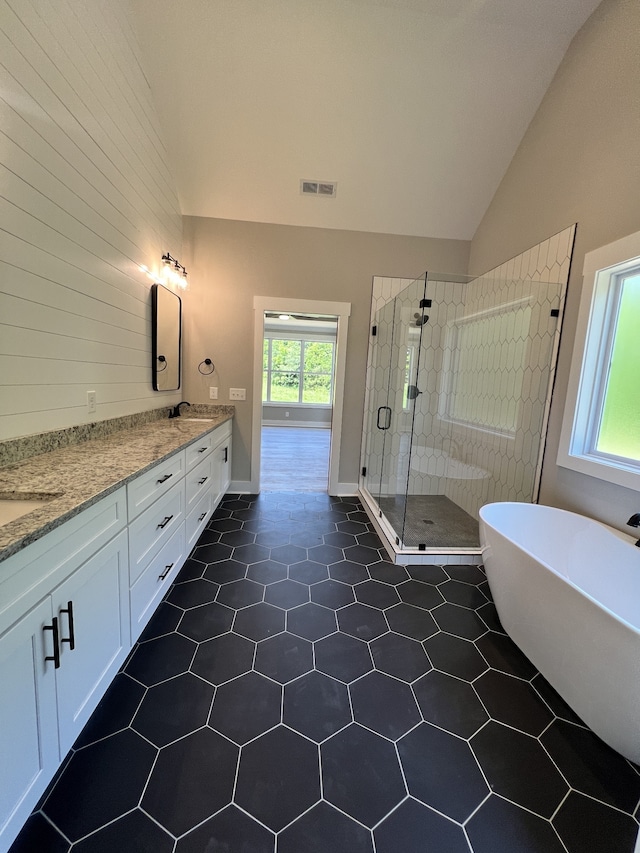 bathroom with shower with separate bathtub, tile patterned flooring, vaulted ceiling, and vanity