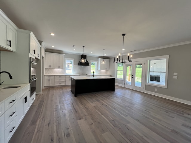 kitchen featuring white cabinets, dark hardwood / wood-style flooring, decorative light fixtures, premium range hood, and sink