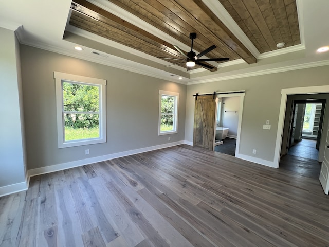 unfurnished bedroom with a barn door, ornamental molding, dark hardwood / wood-style flooring, and ceiling fan