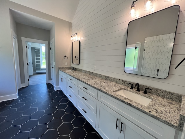 bathroom featuring wood walls, tile patterned flooring, vanity, and vaulted ceiling