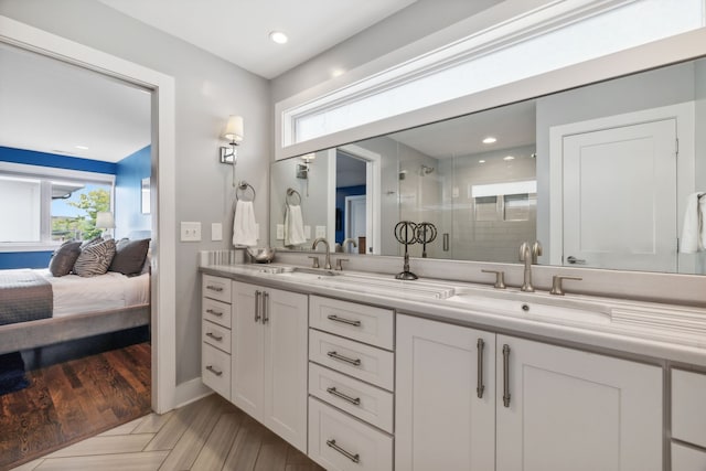 bathroom with a shower with door, hardwood / wood-style floors, and vanity