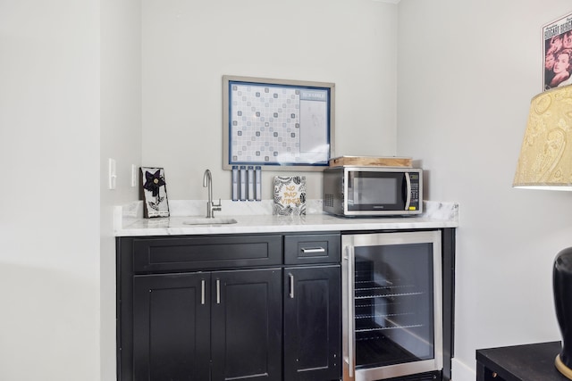 bar with sink, wine cooler, and light stone counters