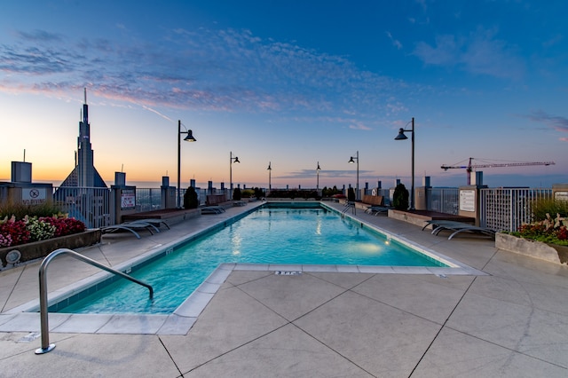 pool at dusk featuring a patio