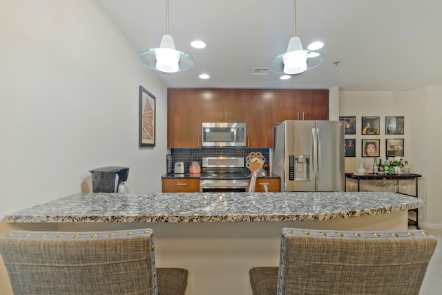 kitchen featuring backsplash, decorative light fixtures, a breakfast bar, and appliances with stainless steel finishes