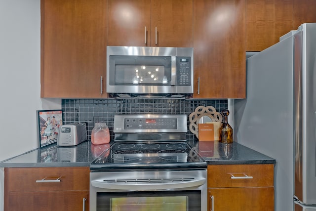 kitchen featuring stainless steel appliances, tasteful backsplash, and dark stone countertops