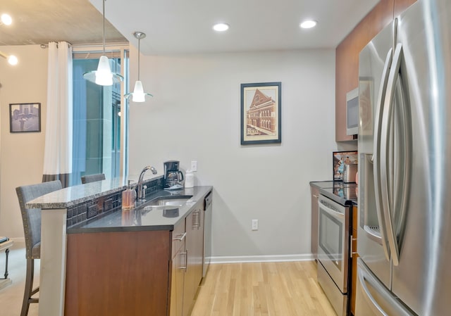 kitchen with kitchen peninsula, a kitchen breakfast bar, stainless steel appliances, sink, and decorative light fixtures