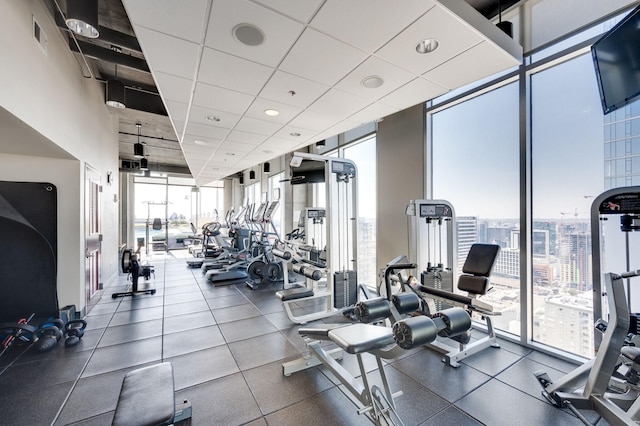 gym featuring a wall of windows, a paneled ceiling, and visible vents