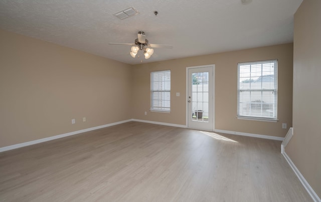 empty room with ceiling fan, a textured ceiling, and light hardwood / wood-style floors