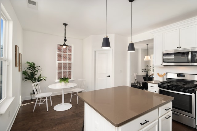 kitchen with a center island, pendant lighting, stainless steel appliances, and white cabinets