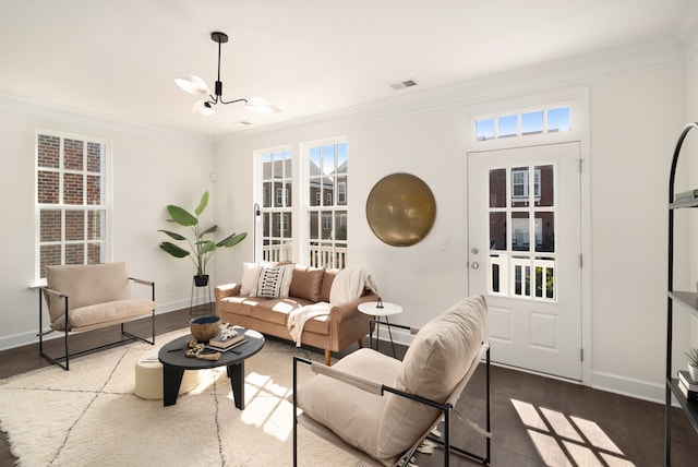 living room featuring ornamental molding, dark wood-type flooring, and a notable chandelier